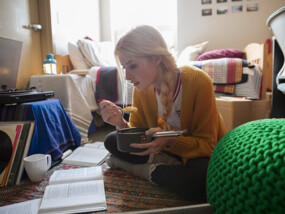 College student eating and studying in her room.