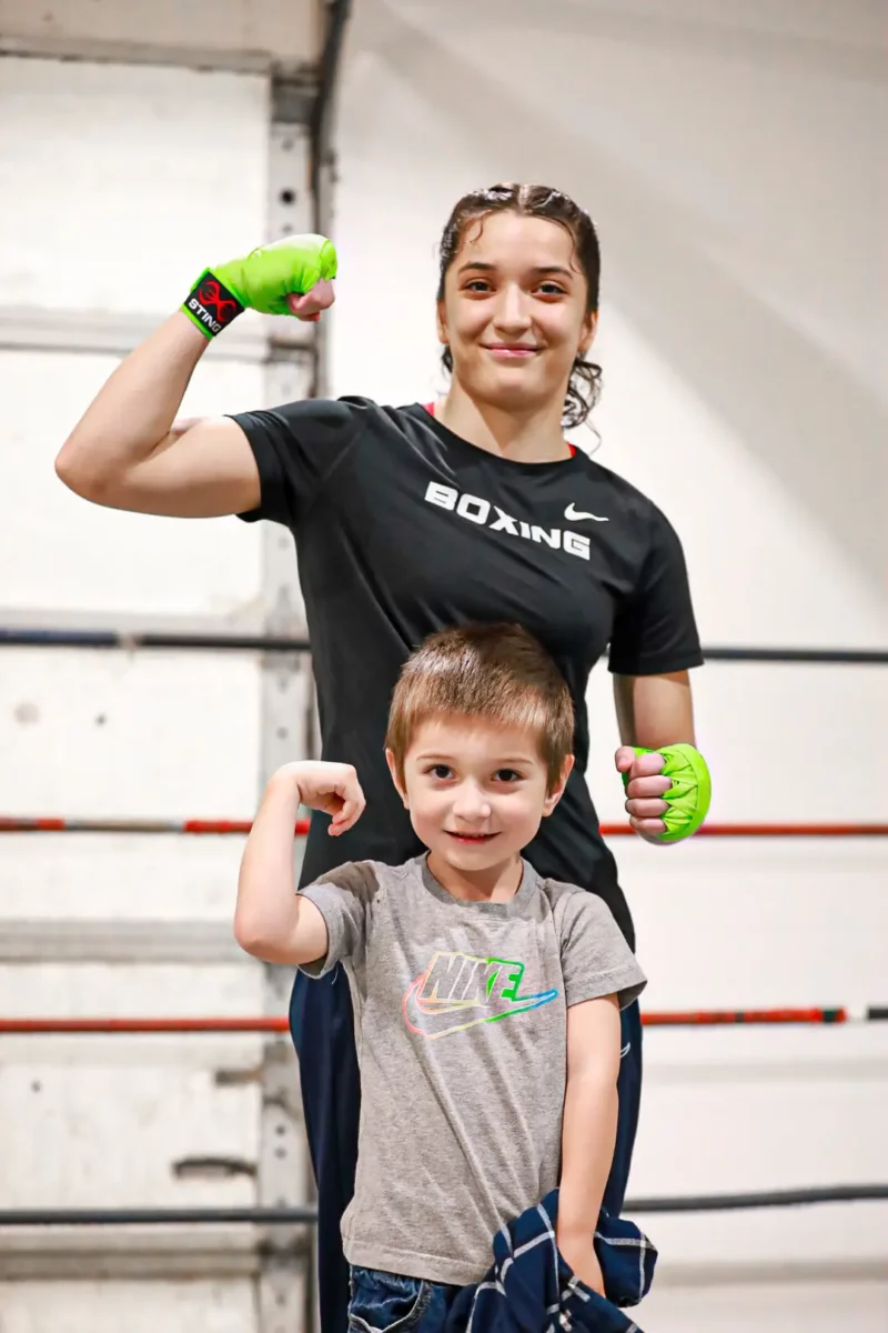 Alyssa Mendoza stands in her at-home boxing ring in Caldwell, Idaho and flexes with her younger brother.