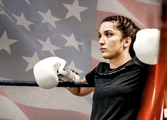 Alyssa Mendoza stands in a boxing ring with an American flag in the background.