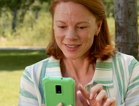 A woman looking at her green smartphone