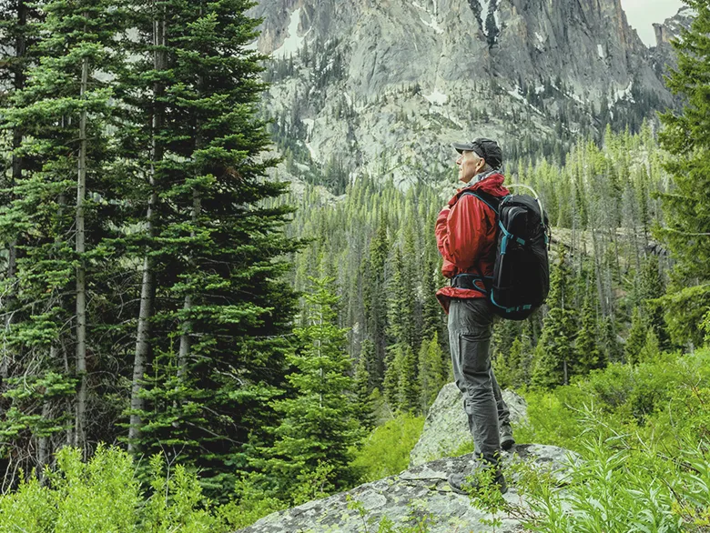 A man wearing a red jacket hiking the mountains