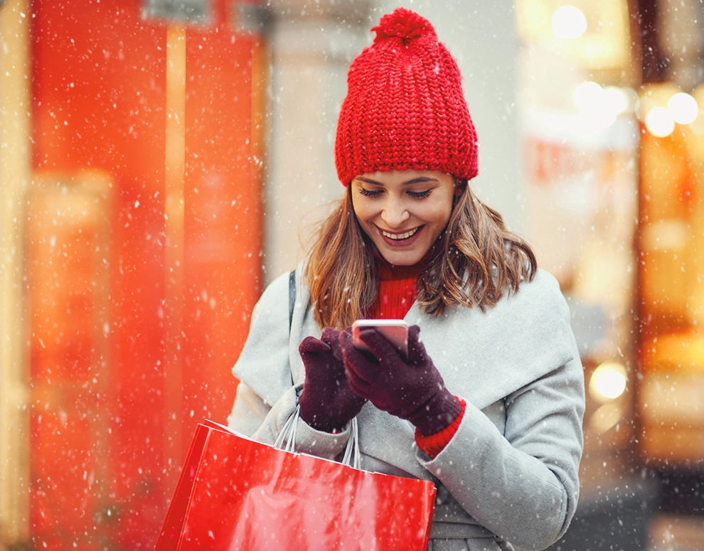 Una mujer con una bolsa de la compra mirando su teléfono