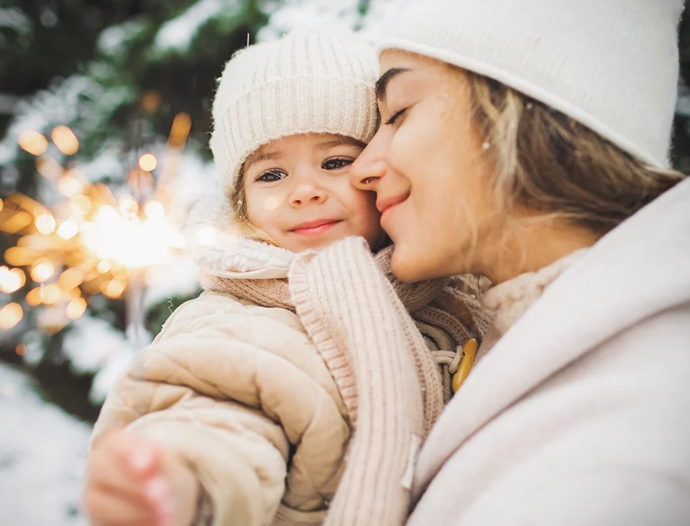 A child with a sparkler being help by her mother