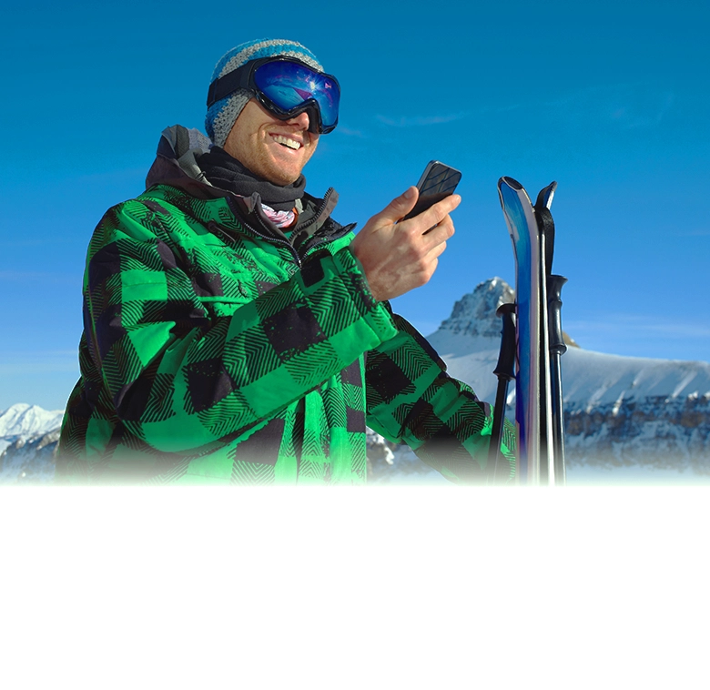 A man looking at his phone while holding ski gear