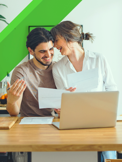 A couple sitting at a table with a laptop and papers